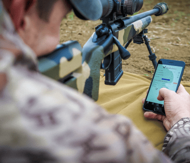 A photograph of a hunter using Geoballistics app.